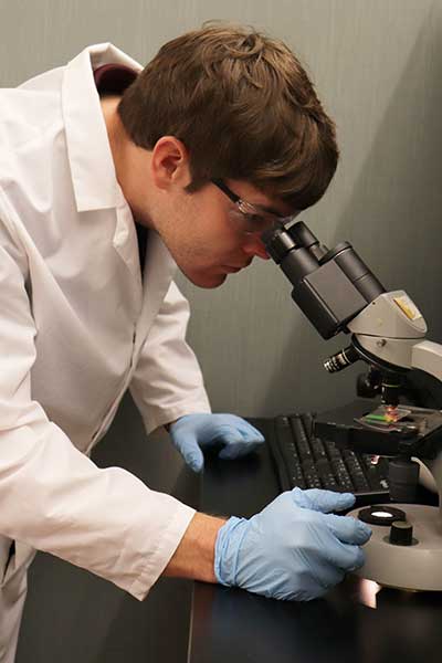 a lab worker staring into a microscope