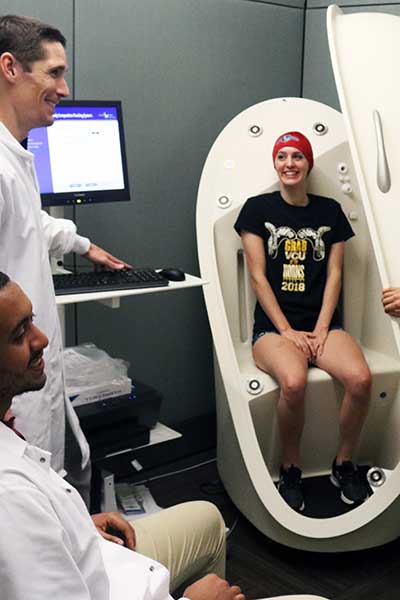 a research participant speaks with kinesiology researchers before being closed up into a test chamber