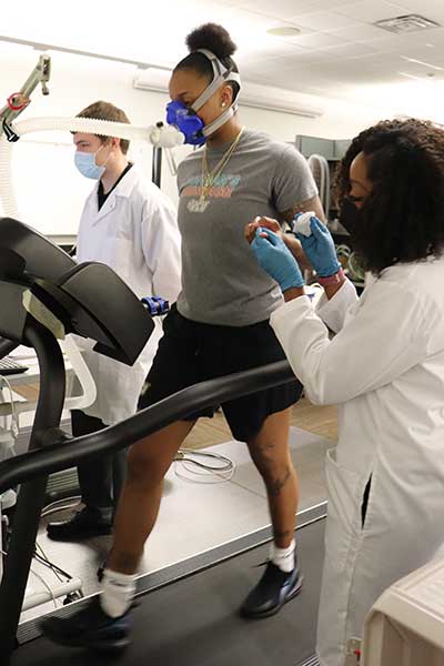 kinesiology researchers monitoring oxygen levels and pulse rates of a runner on a treadmill
