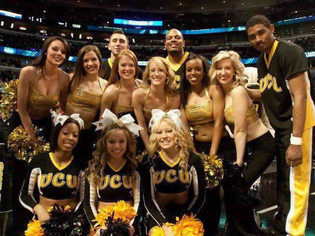 A group of VCU cheerleaders pose in a baskeball arena