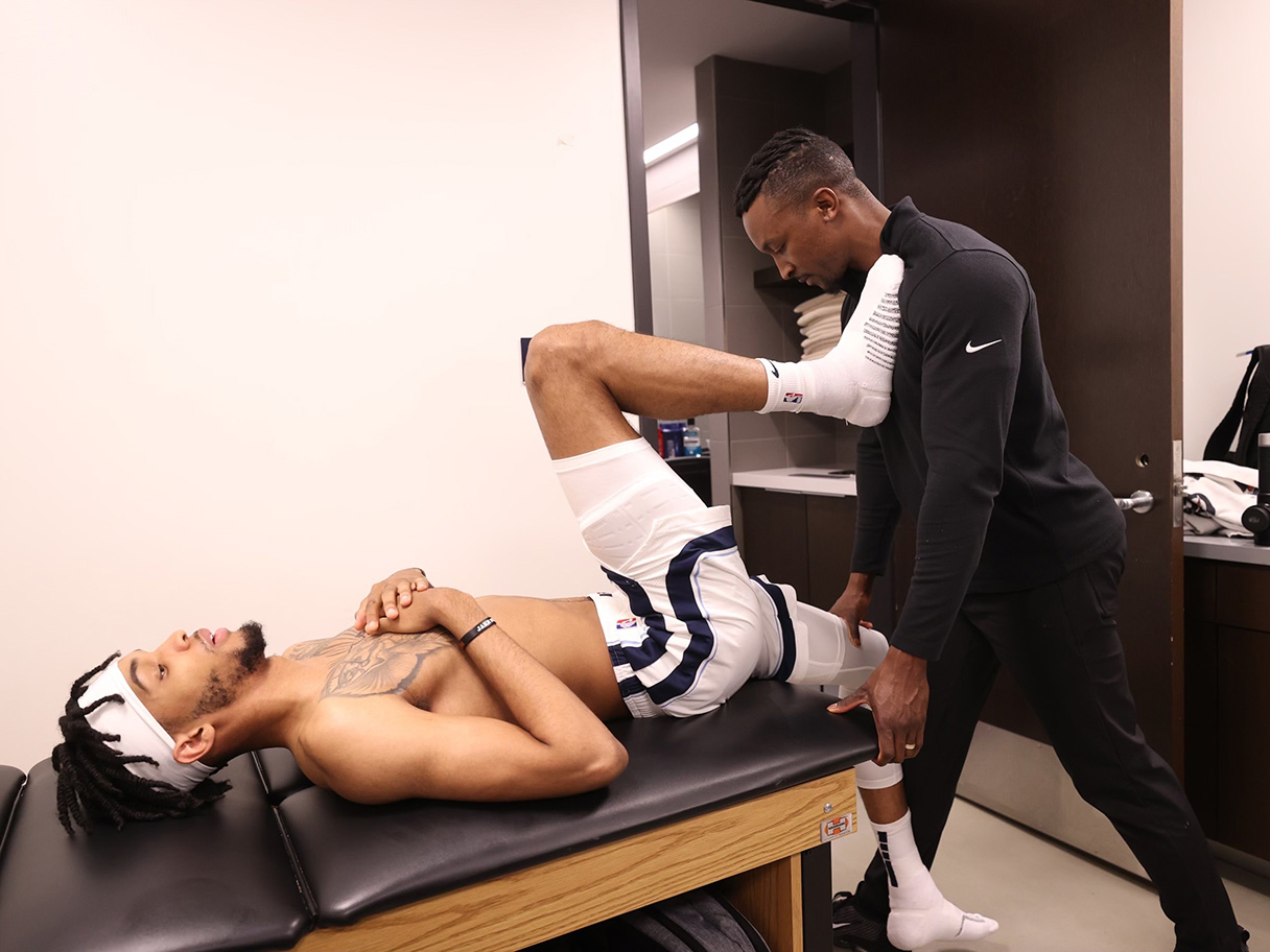 Jarred Boyd assists an athlete with a leg stretch